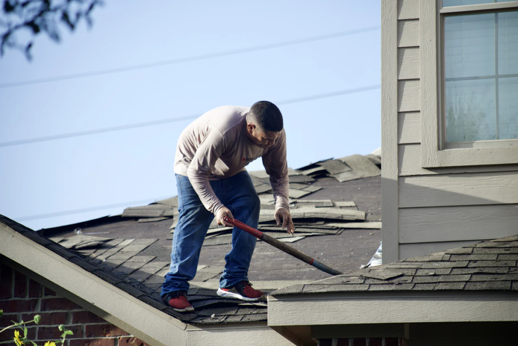 Roofer removing damaged shingles during a roof repair