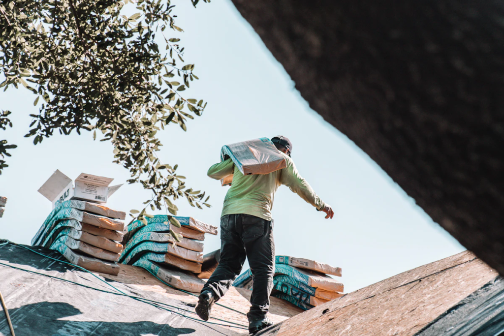 Roofer carrying a bundle of shingles during a roof replacement